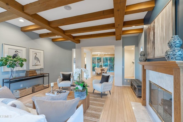 living room with beam ceiling, a tile fireplace, coffered ceiling, and light wood-type flooring