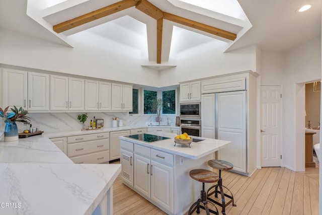 kitchen with built in appliances, a center island, high vaulted ceiling, and light hardwood / wood-style floors