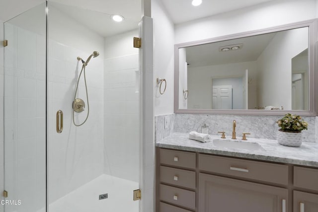 bathroom with backsplash, a shower with door, and vanity