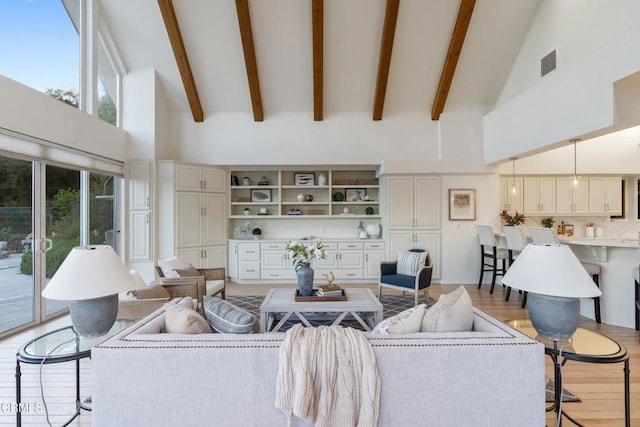 living room with beam ceiling, light hardwood / wood-style flooring, and high vaulted ceiling