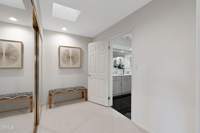 corridor featuring a skylight and light carpet