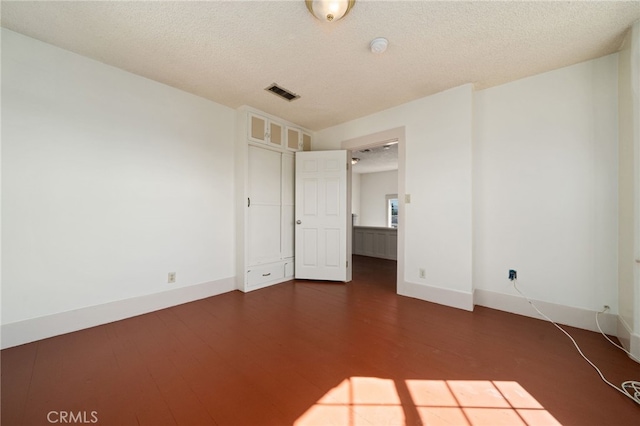 unfurnished bedroom with a textured ceiling and dark wood-type flooring