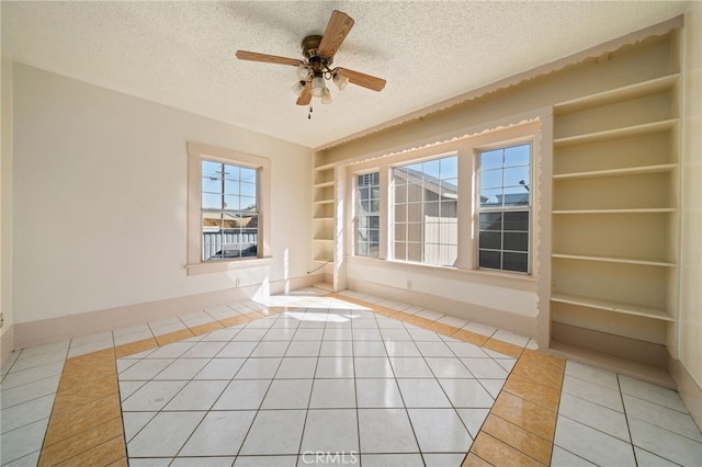 unfurnished room with a textured ceiling, ceiling fan, light tile patterned floors, and built in features