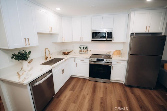 kitchen with sink, stainless steel appliances, light stone countertops, hardwood / wood-style floors, and white cabinets