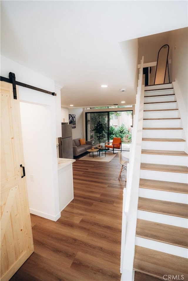 stairs with a barn door and hardwood / wood-style floors