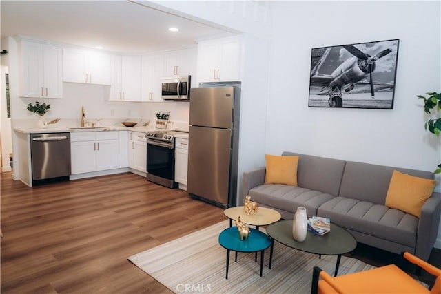 kitchen with stainless steel appliances, sink, wood-type flooring, and white cabinets