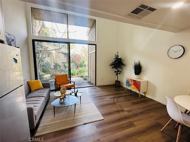 living room with dark wood-type flooring and a high ceiling