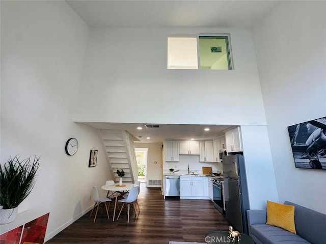 living room with a high ceiling, sink, and dark wood-type flooring