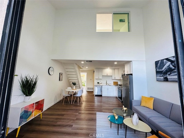 living room featuring dark hardwood / wood-style floors, sink, and a high ceiling