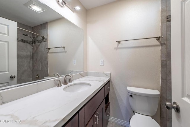 bathroom with vanity, toilet, and a tile shower