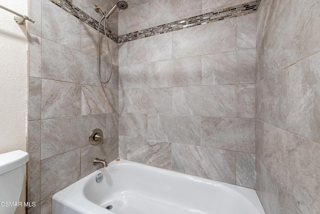 bathroom featuring tiled shower / bath combo and toilet