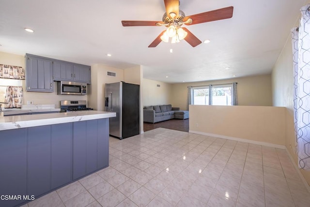 kitchen with kitchen peninsula, ceiling fan, light tile patterned flooring, and stainless steel appliances