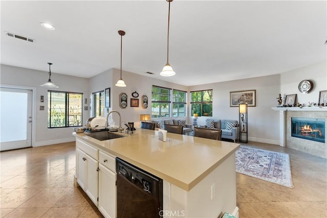 kitchen featuring dishwasher, sink, a healthy amount of sunlight, and an island with sink