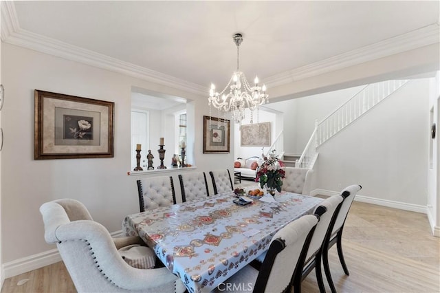 dining area featuring light hardwood / wood-style floors, crown molding, and a notable chandelier