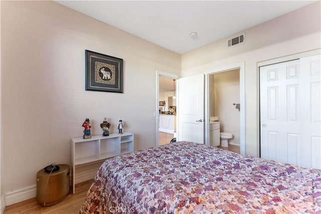 bedroom featuring hardwood / wood-style floors, ensuite bath, and a closet