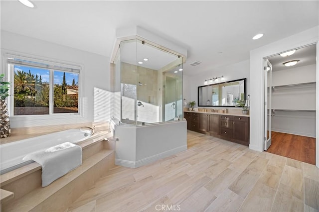 bathroom featuring vanity, hardwood / wood-style floors, and plus walk in shower