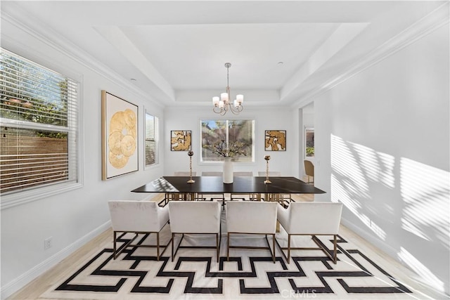 dining area featuring a tray ceiling, crown molding, light wood-type flooring, and a notable chandelier