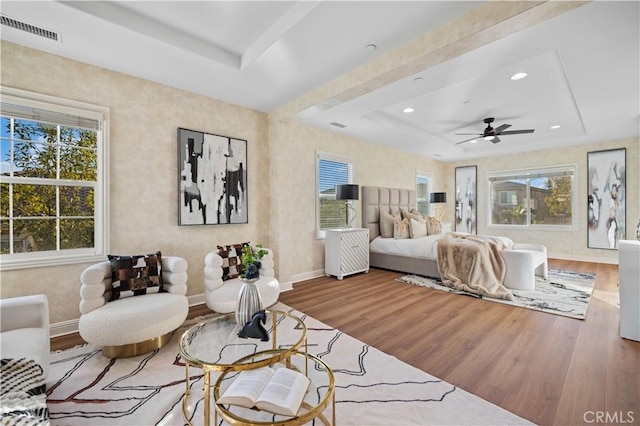 bedroom featuring a raised ceiling, ceiling fan, and hardwood / wood-style floors