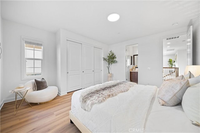 bedroom featuring hardwood / wood-style floors, a closet, and ensuite bath