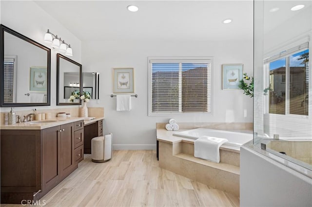 bathroom with a washtub, wood-type flooring, and vanity