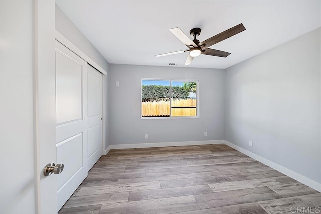 unfurnished bedroom featuring light wood-type flooring, a closet, and ceiling fan