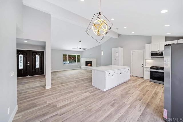 kitchen featuring white cabinetry, hanging light fixtures, stainless steel appliances, light hardwood / wood-style floors, and vaulted ceiling