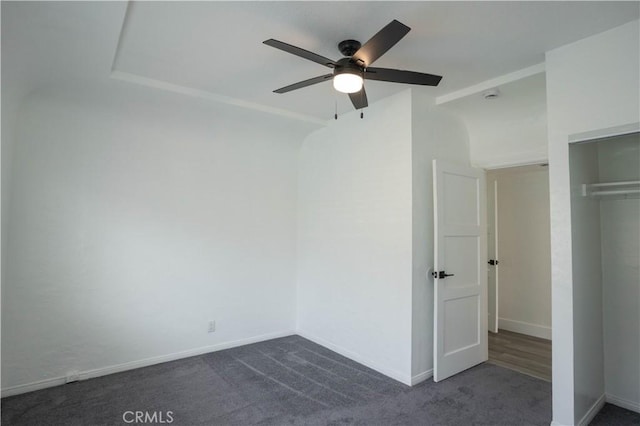 unfurnished bedroom with dark colored carpet, ceiling fan, and a closet