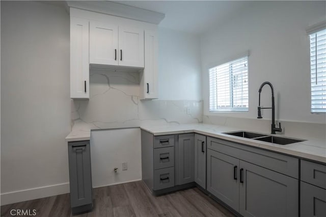 kitchen with light stone countertops, gray cabinetry, dark wood-type flooring, sink, and white cabinets