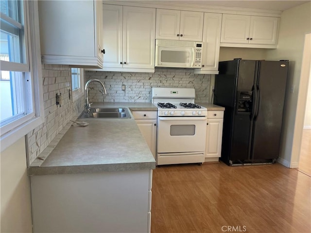 kitchen featuring white cabinetry, sink, light hardwood / wood-style flooring, white appliances, and decorative backsplash