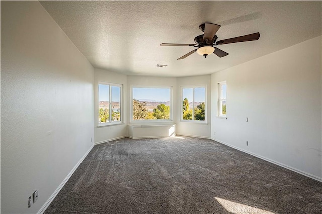 spare room with ceiling fan, dark carpet, and a textured ceiling