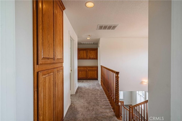 corridor with carpet floors and a textured ceiling