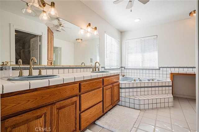 bathroom featuring tile patterned floors, tiled bath, ceiling fan, and vanity