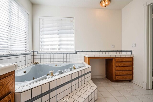 bathroom with tile patterned flooring, vanity, and a relaxing tiled tub