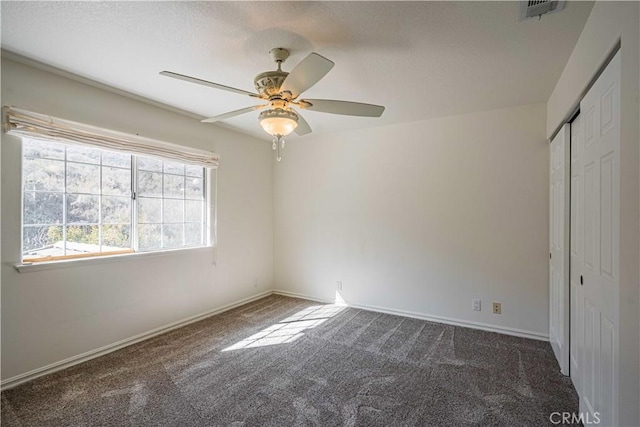 unfurnished bedroom featuring dark colored carpet, ceiling fan, and a closet