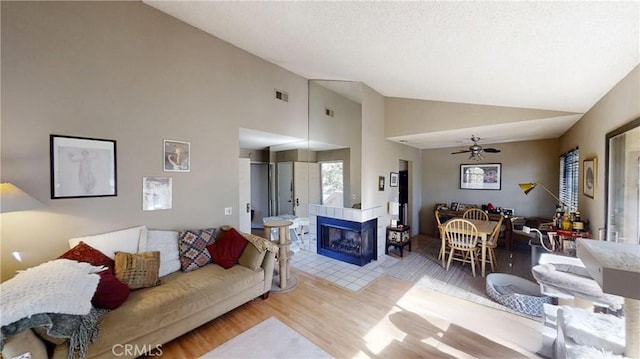 living room with a fireplace, ceiling fan, hardwood / wood-style floors, and high vaulted ceiling