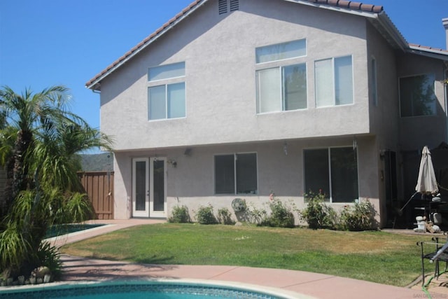 back of property with a yard and french doors