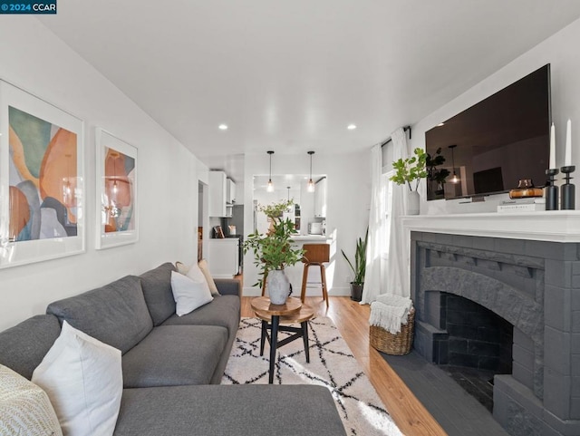 living room featuring a tiled fireplace and light hardwood / wood-style floors