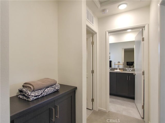 hall featuring sink and light tile patterned floors