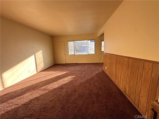 carpeted spare room with wood walls