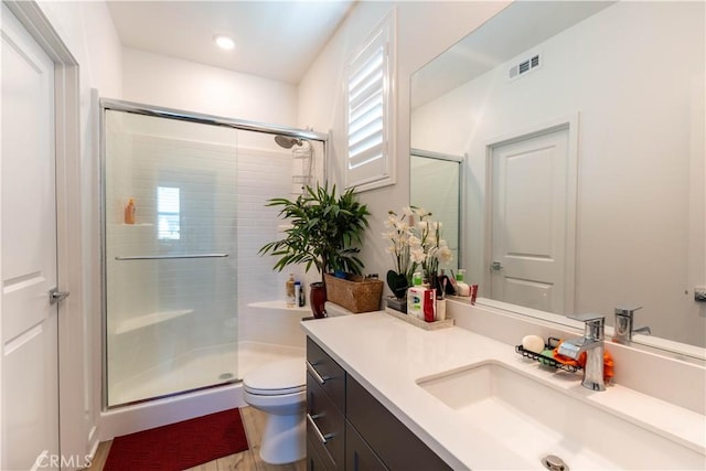 bathroom featuring an enclosed shower, vanity, toilet, and hardwood / wood-style flooring