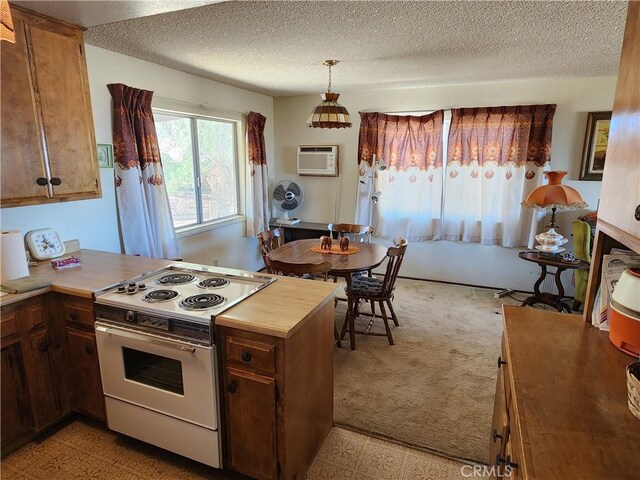 kitchen featuring decorative light fixtures, light colored carpet, a wall mounted AC, white range with electric cooktop, and a textured ceiling