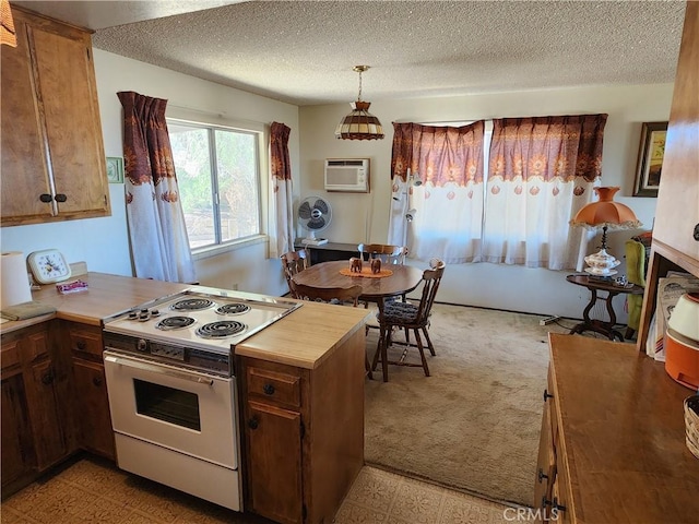 kitchen with light countertops, pendant lighting, electric range, and a wall mounted air conditioner