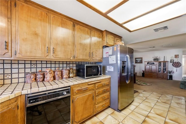 kitchen with tasteful backsplash, visible vents, tile counters, and stainless steel appliances