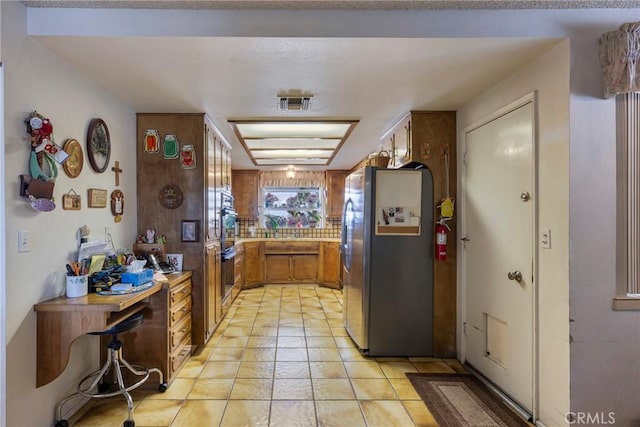 kitchen featuring multiple ovens, light countertops, and freestanding refrigerator