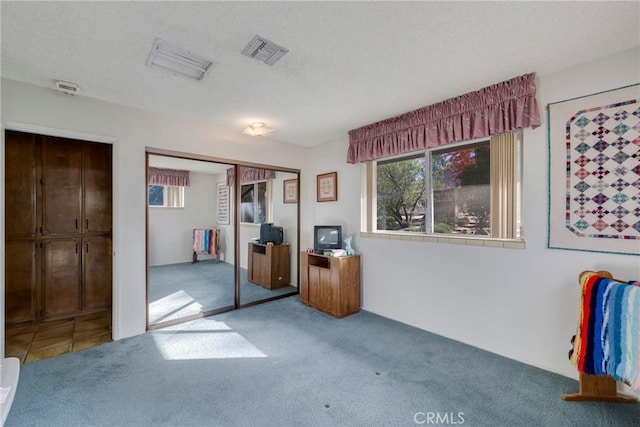 unfurnished bedroom with carpet, a textured ceiling, visible vents, and a closet