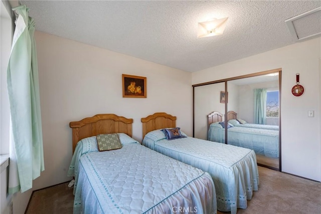 bedroom featuring carpet floors, attic access, a closet, and a textured ceiling