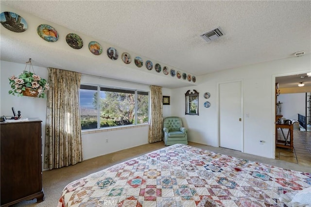 bedroom with visible vents, light colored carpet, and a textured ceiling