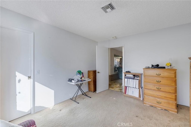 bedroom featuring a textured ceiling, visible vents, and light carpet