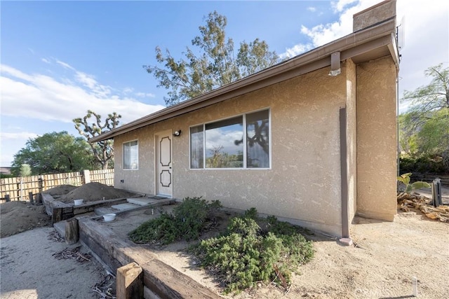 view of home's exterior with fence and stucco siding