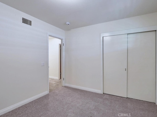 unfurnished bedroom featuring light colored carpet and a closet